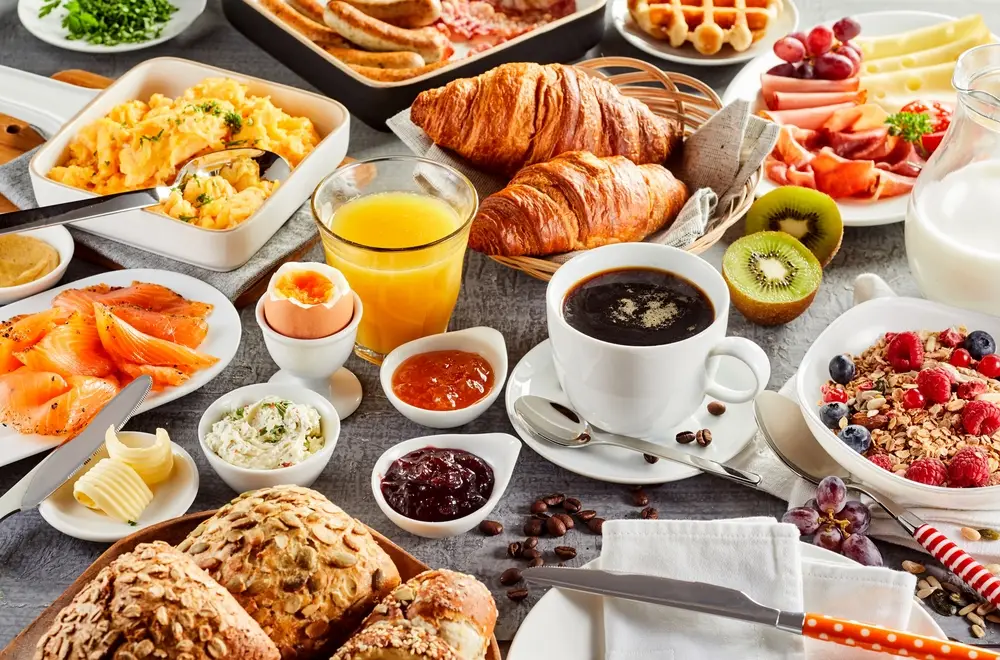 The Old Parkes Convent. Huge healthy breakfast spread on a table with coffee, orange juice, fruit, muesli, smoked salmon, egg, croissants, meat and cheese.