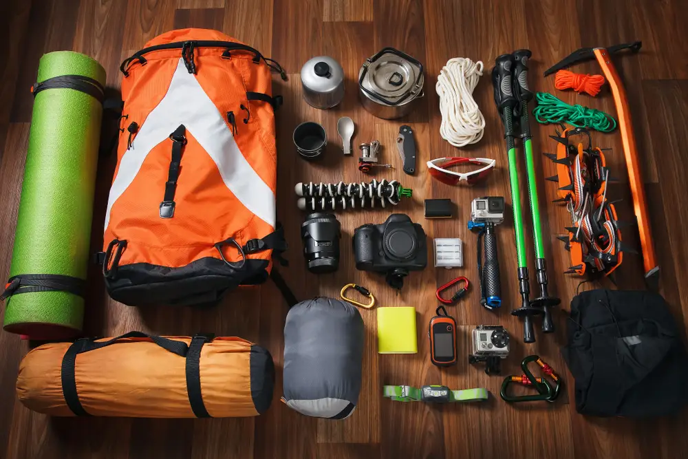 Ayson’s Reserve. Equipment for mountaineering and hiking on wooden background. Climbing equipment: rope, trekking shoes, crampons, ice tools, ice ax, ice screws, red knife and other set on dark wooden background.