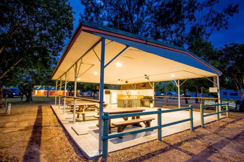 A covered BBQ area in the evening with lights on at Discovery Parks Tannum Sands