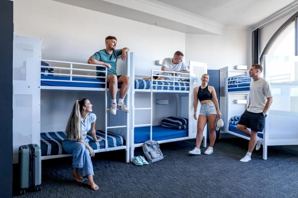 Mixed dormitoriy with three bunk beds with fresh linen and travellers taling amongst themselves at Hostel Wake Up! Sydney Central 