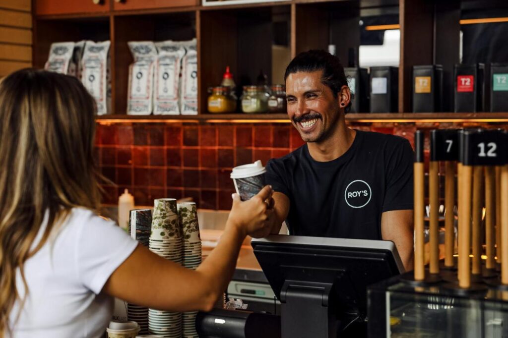 A traveller recieveing a cup of coffee from staff at Roys cafe/bar at Hostel Wake Up! Sydney Central