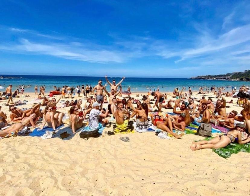 Hostel guests relaxing in the beach across the road at Mad Monkey Hostel Coogee Beach
