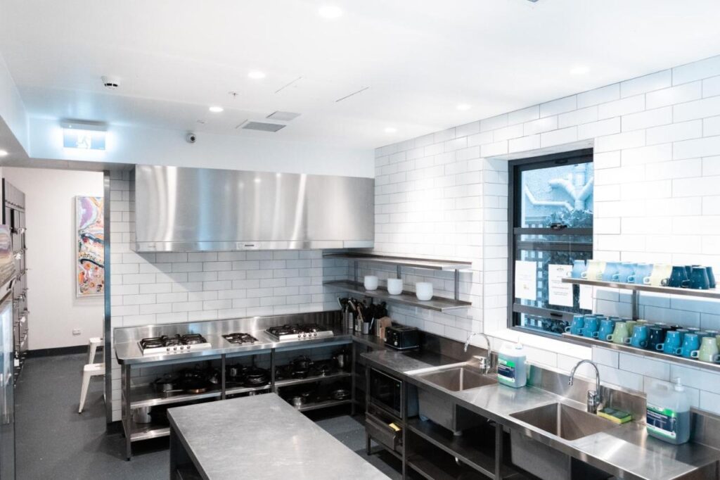 A shared kitchen space with stainless steel bench tops for travellers to cook their own lunches and dinners at Wake Up! Bondi Beach 