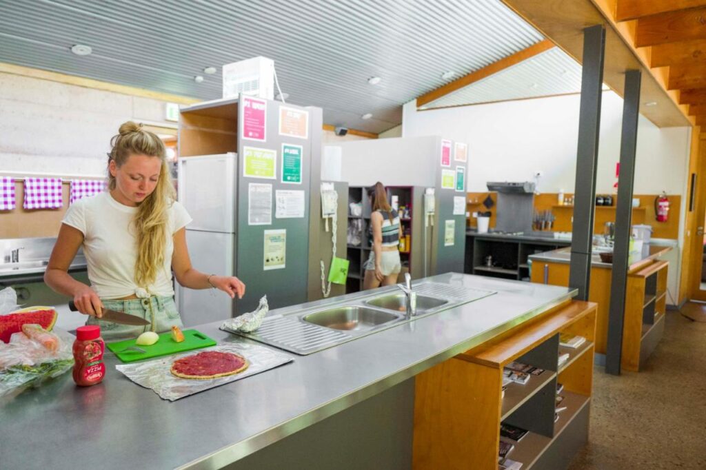 A traveller making a pizza in the kitchen at YHA Grampians Eco, Halls Gap 