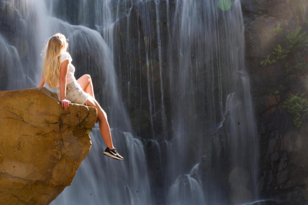 A traveller sitting on a rock beside MacKenzie Falls near YHA Grampians Eco Halls Gap