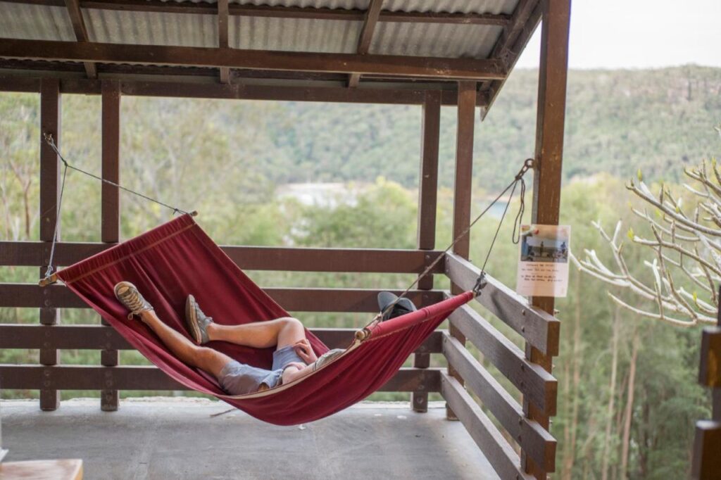 A traveller relaxing on a hammock soaking in wellness at YHA Pittwater Eco Sydney