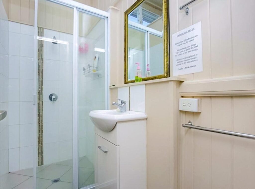 A clean and well maintained modern bathroom showing a ssnk, mirror and shower at Bunk Inn Hostel