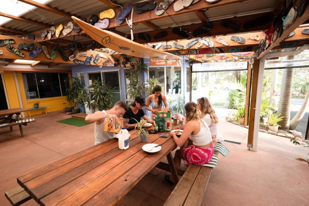 Some travellers sitting on the communal outdoor terrace having breakfast or having breakfast for dinner at Ozzie Pozzie Backpackers