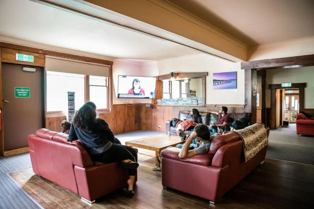 A few travellers relaxing on the lounges while watching a movie at The Pickled Frog Hostel.